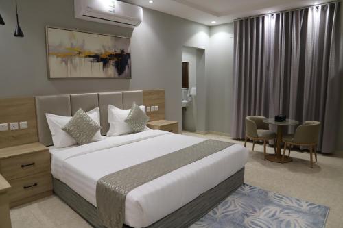 a bedroom with a large white bed and a table at اجنحة نزيل & اجنحة الشمال in Tabuk