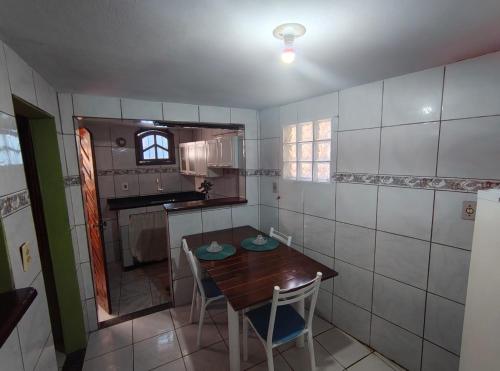een kleine keuken met een houten tafel en stoelen bij Jully's house in Arraial do Cabo