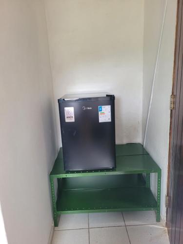 un piccolo scaffale verde in una stanza con un microonde di Sítio Guanabara a Guaramiranga