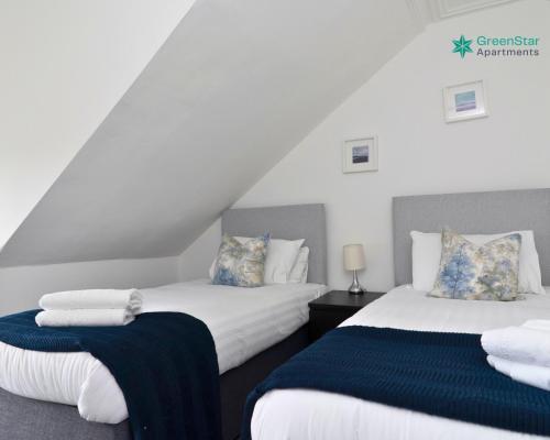 twee bedden met blauwe en witte lakens in een kamer bij GreenStar Apartments - Short Walk Away Into Dundee City Centre - Next To Abertay University - Perfect For Your Short or Long Stays - Weekly & Monthly Offers For Your Longer Stays - CLICK FOR OPTIONS - 6 PROPERTIES AVAILABLE FROM 1 TO 3 BEDROOMS in Dundee