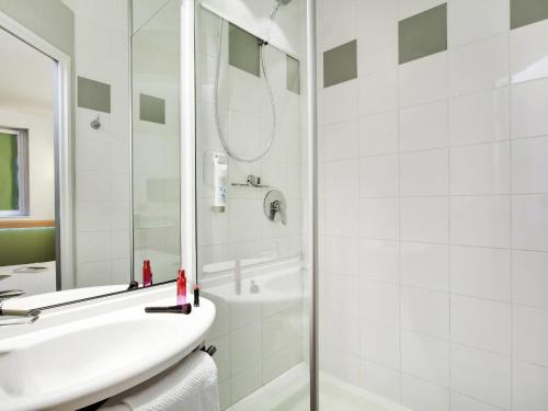 ein weißes Badezimmer mit Waschbecken und Dusche in der Unterkunft ibis Budget Clermont Ferrand Centre Montferrand in Clermont-Ferrand
