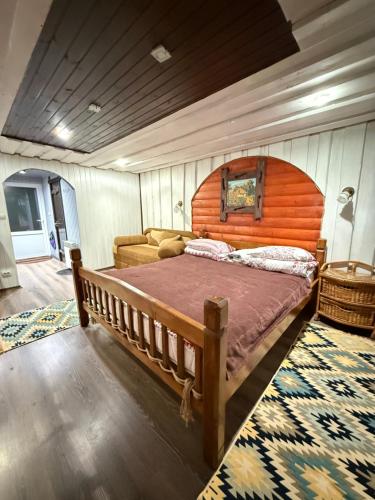 een slaapkamer met een groot bed met een houten hoofdeinde bij У Віти номер 4 in Synevyrsʼka Polyana