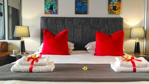 ein Schlafzimmer mit roten Kissen und Handtüchern auf einem Bett in der Unterkunft Menlyn Maine Residences - Superior king - Paris apartment in Pretoria