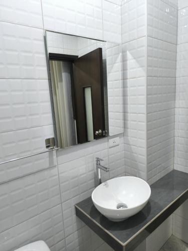 een witte badkamer met een wastafel en een spiegel bij Hotel Belle Maison in Chiclayo