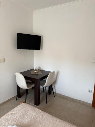 a dining room table with two chairs and a television on a wall at Apartmani Marković in Tivat