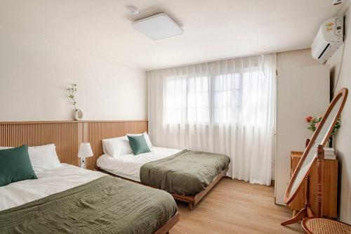 a hotel room with two beds and a window at Pachira House in Seoul