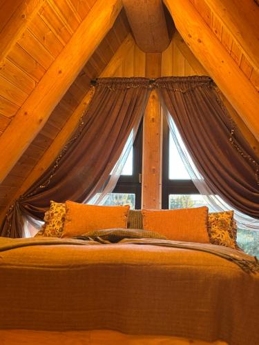 a bed in a room with a large window at Premiere Chalet in Vărşag