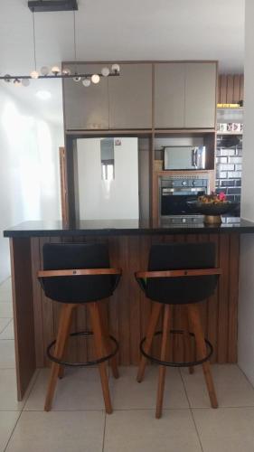 eine Küche mit einer Theke mit zwei Barhockern in der Unterkunft Lar Sousa Rocha in Capão da Canoa