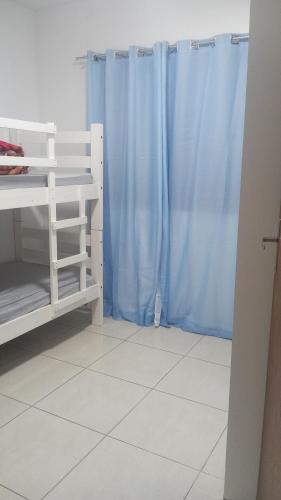 ein Schlafzimmer mit blauen Vorhängen und weißem Boden in der Unterkunft Lar Sousa Rocha in Capão da Canoa