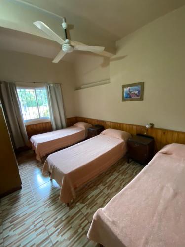 een kamer met 3 bedden en een plafondventilator bij Casa en complejo in San Roque