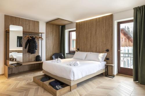 a bedroom with a large white bed and a window at B&B Hotel Passo Tre Croci Cortina in Cortina dʼAmpezzo