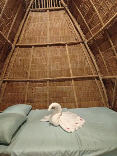 a white swan is sitting on a bed in a tent at El Hermosa Bice Camp in El Nido