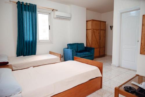 a bedroom with two beds and a blue chair at Smouha Hotel in Alexandria