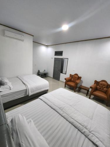 a room with two beds and two chairs in it at Champrink Surfcamp in Wainapal