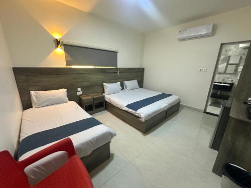 a hotel room with two beds and a chair at Happy Beach Castel for Apartment قلعة شاطئ السعادة للشقق المفروشة in Aqaba