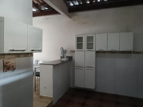 eine Küche mit weißen Schränken und einer Arbeitsplatte in der Unterkunft Casa no Centro da cidade! in Goiás