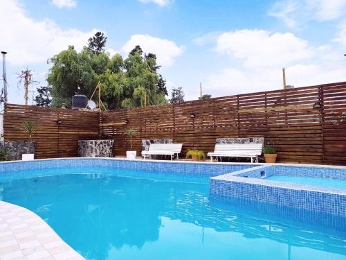 a swimming pool with two chairs and a wooden fence at Gran Lourdes Hotel in Villa Carlos Paz