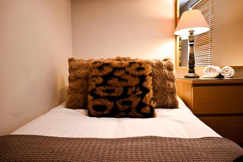 a bedroom with a bed with a brown blanket and a lamp at The Walmer Retreat in Deal