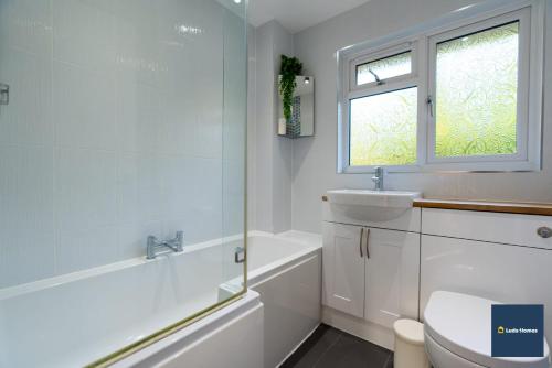 a bathroom with a sink and a toilet and a window at Camberley Spacious and Comfy 3 Bedroom Home, Next to Frimley Hospital with Parking in Frimley
