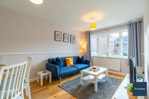 a living room with a blue couch and a table at Camberley Spacious and Comfy 3 Bedroom Home, Next to Frimley Hospital with Parking in Frimley