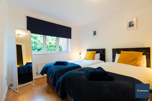 a bedroom with two beds and a large mirror at Camberley Spacious and Comfy 3 Bedroom Home, Next to Frimley Hospital with Parking in Frimley