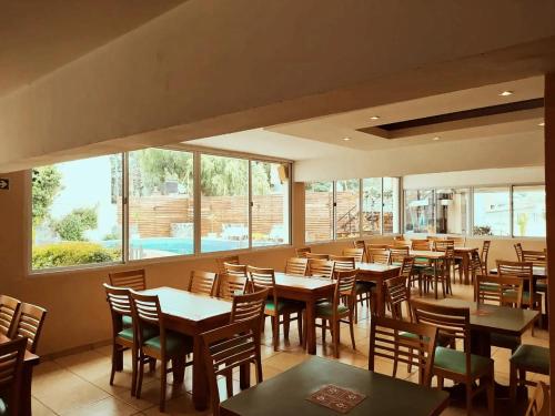 a restaurant with wooden tables and chairs and windows at Gran Lourdes Hotel in Villa Carlos Paz