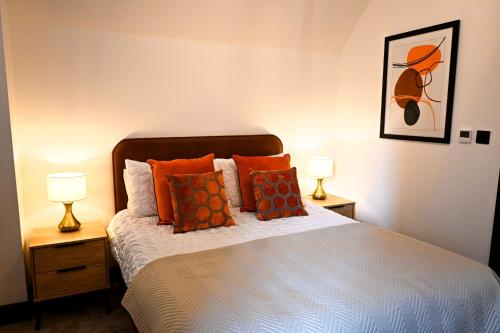 a bedroom with a bed with orange pillows and two lamps at Laurie Grove in London