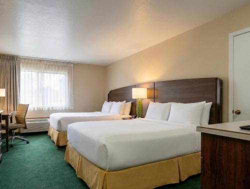 een hotelkamer met twee bedden en een bureau bij Rogue Regency Inn Medford Airport in Medford