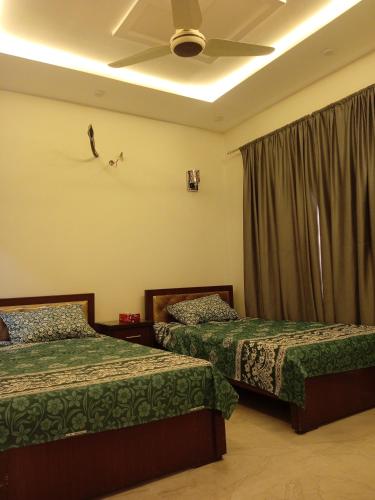 a bedroom with two beds and a ceiling at Bahria town karachi Volka Guest House in Karachi