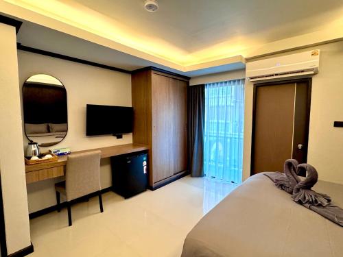 a hotel room with a bed and a desk and a television at Black Pantera House in Patong Beach
