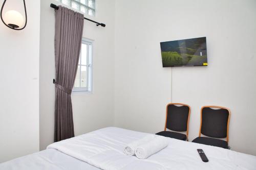 a bedroom with a bed and two chairs at Clarissa Guest House Cisarua Bandung in Sukaraja