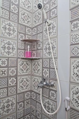 a shower in a bathroom with a tile wall at Clarissa Guest House Cisarua Bandung in Sukaraja