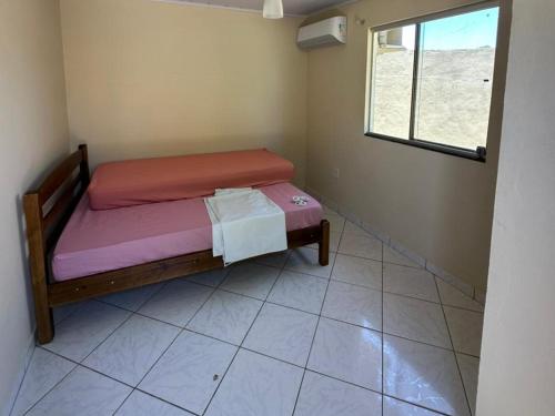 a small bed in a room with a window at Casa Fantástica in Guriri