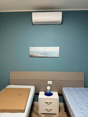 een kamer met 2 bedden en een nachtkastje met een bed sidx sidx bij Aubry Appartament in Praia a Mare