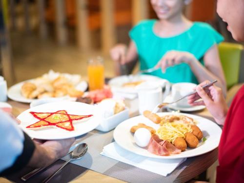 een groep mensen aan een tafel met borden eten bij Ibis Styles Dragon Mart Dubai in Dubai
