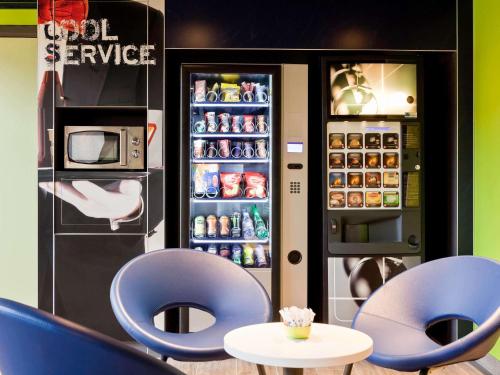 een restaurant met twee blauwe stoelen en een koelkast bij ibis budget Pontault Combault RN4 Marne La Vallée in Pontault-Combault