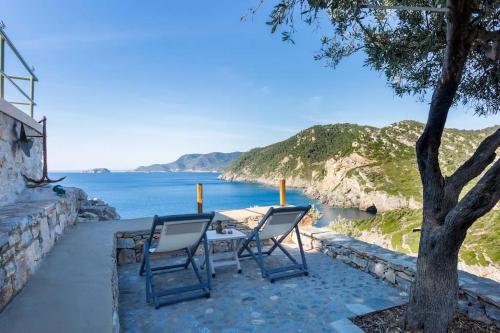 two chairs and a table next to the ocean at Casa Milos Aegean Suites in Alonnisos