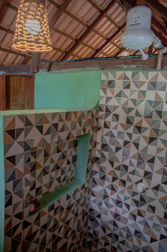 a bathroom with a tile wall and a light at Bangalôs Suítes na Floresta Encantada in Santarém