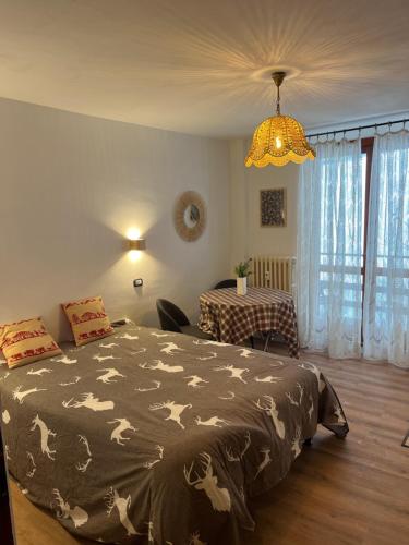 a bedroom with a bed and a table and a chandelier at Appartamento Moon River Monolocale in Limone Piemonte