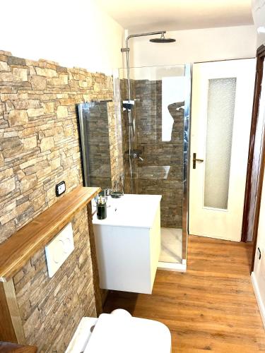 a bathroom with a white sink and a stone wall at Appartamento Moon River Monolocale in Limone Piemonte