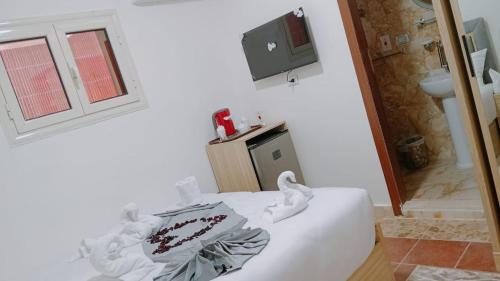 Camera con letto bianco e TV a parete. di apartment pyramids view a Giza