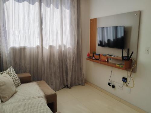 ein Wohnzimmer mit einem Sofa und einem TV an der Wand in der Unterkunft Conforto, Lazer e Localização Estratégica em Maceió! in Maceió