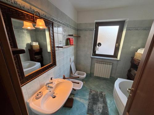 een badkamer met een wastafel, een bad en een spiegel bij Fusero1 relax vero borgata fusero 20 giaveno in Coazze