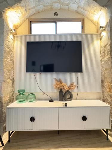 ein weißes Entertainment-Center mit einem Flachbild-TV darüber in der Unterkunft בר יוחאי העתיקה in Safed