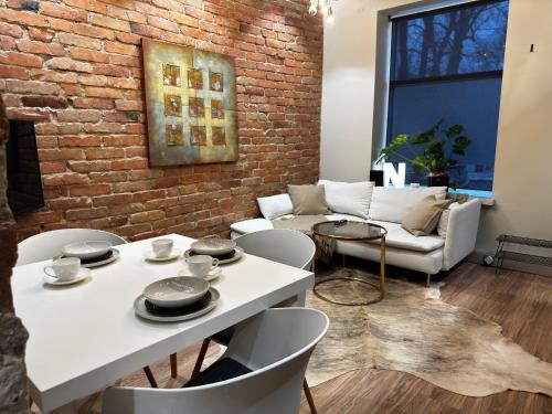 ein Wohnzimmer mit weißen Tischen und Stühlen und einer Backsteinwand in der Unterkunft Casa Rustica Free Parking Port Arthur in Turku