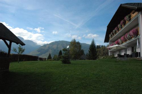 a green field next to a building with mountains in the background at Appartement Haus Moser in Sankt Michael im Lungau