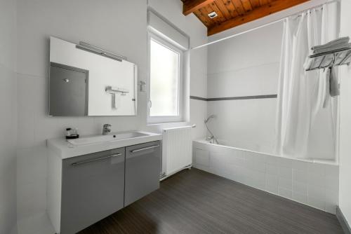 a white bathroom with a sink and a mirror at Hôtel De La Plage in Le Chambon-sur-Lignon