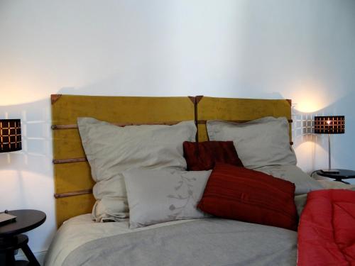 a bed with white and red pillows on it at Les Viviers Maison d'hôtes B&B in Puiseaux