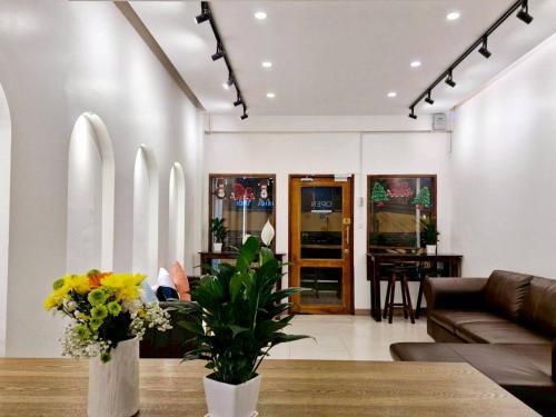 a living room with a couch and a table with flowers at MaMa Hostel CNX in Chiang Mai