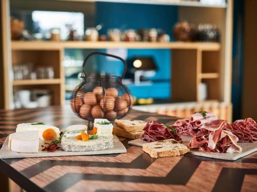 une table en bois avec différents types de nourriture dans l'établissement Mercure Lyon Genas Eurexpo, à Genas
